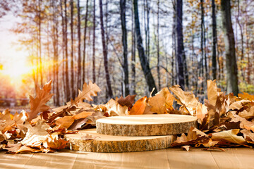 Wall Mural - Autumn leaves and wooden pedestal on wooden table with warm autumn sunlight and forest trees background. Copy space for products.