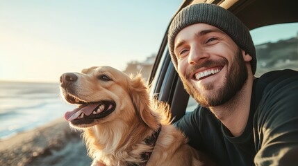 Smiling man wearing beanie, with his dog by his side, both leaning out of a car window and feeling the wind in their hair and fur, against a backdrop of a bright, sunny day