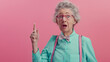 © Lahiru - A surprised senior woman points a finger at an empty space on a pink background. for promotion or offer advertisement. copy space.