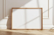 © timitinej - One frame on floor mockup blank poster. Wooden frame mock up empty print background. Wood picture frame in room. Gallery design realistic modern interior