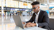 © niwat - young black businessman using his laptop at the airport waiting for his flight