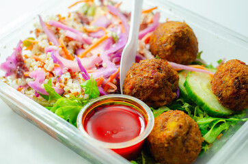 A salad with meatballs and a dipping sauce