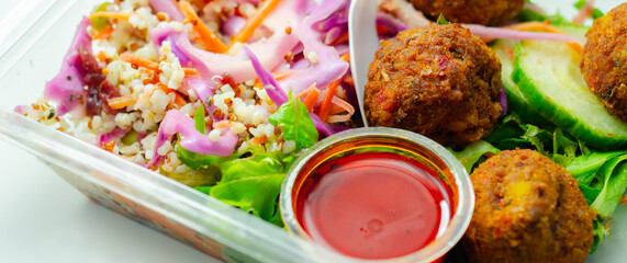 A salad with meatballs and a dipping sauce