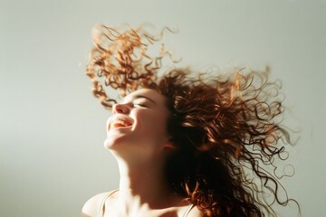 A person joyfully tossing their curly hair, with bright sunlight enhancing the dynamic motion, epitomizing freedom.