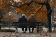 © DK_2020 - An elderly couple sitting on a park bench, holding hands surrounded by autumn leaves, long term relationships