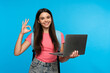 © InsideCreativeHouse - Young teenager high school girl holding laptop computer showing okay gesture while using it for surfing webpages on Internet, social media posting,e-learning remotely isolated in blue background