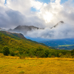 Wall Mural - mountain valley in dense mist and clouds in light of sun