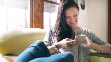 Wall Mural - Woman, phone and smile on sofa for reading text, social media and dating site registration in home. Female person, mobile and happy for chat app with networking, communication and online blog update