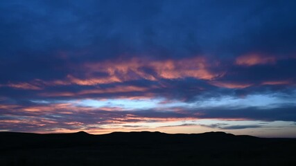 Wall Mural - time lapse of late day blue colored clouds that start out with pink highlights then fade to dark blu