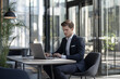 © BetterPhoto - A businessman in a modern office working on a laptop, surrounded by glass walls and natural light, conveying professionalism and focus.