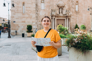 Young beautiful 30s woman looking city map at street, old town. Attractive young female tourist is exploring new city. Traveling Europe, High quality photo