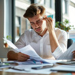 © Bilal - Young confused businessman analyzing documents