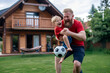 © GraysonStock - A father playing with his son in his backyard, playing with a soccer ball.