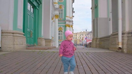 Wall Mural - A child toddler girl walks in the center of St. Petersburg near the Winter Palace.