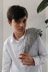 Wall Mural - Handsome teenager standing near the window indoors and looking at camera