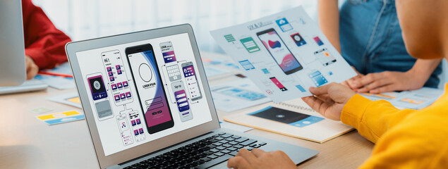 Panorama banner of startup UX developer or company employee design user interface or UI prototype for mobile application or website software with software display on laptop monitor in office. Synergic
