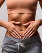 © juanorihuela - Close-up of a flat female abdomen with a slim young woman placing her hands on her stomach. Healthy life concept. Possible menstrual pain.