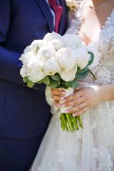 Wall Mural - The bride in a white dress holds a bouquet of fresh flowers in her hands. Bride's bouquet.