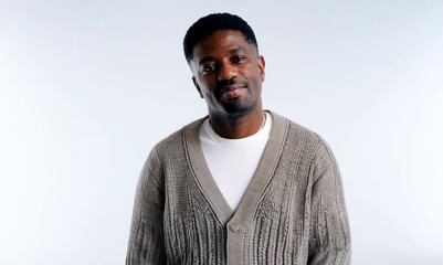 Wall Mural - Medium shot portrait of a Nigerian man in his 40s in a white background wearing a chic cardigan