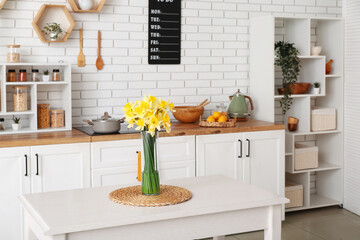 Wall Mural - Vase with blooming narcissus flowers on table in interior of kitchen