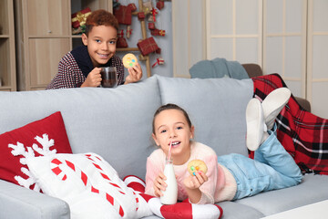 Poster - Little children eating cookies with milk and hot chocolate at home on Christmas eve