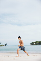 Wall Mural - Muscular Asian Athlete Running on the Beach at Sunset, Exuding Fitness and Strength