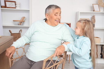 Sticker - Cute little girl with her granny sitting in chair at home