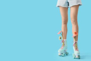 Wall Mural - Female legs in roller skates with gerbera flowers on blue background