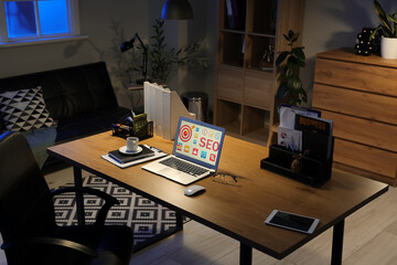 Sticker - Laptop with abbreviation SEO on desk in dark office