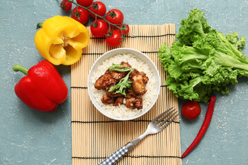 Wall Mural - Tasty sweet and sour chicken with rice in bowl, mat and vegetables on turquoise grunge background