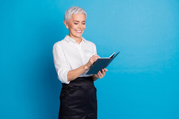 Sticker - Photo of pretty retired female write order notebook barista small coffee shop owner wear waitress uniform isolated on blue color background