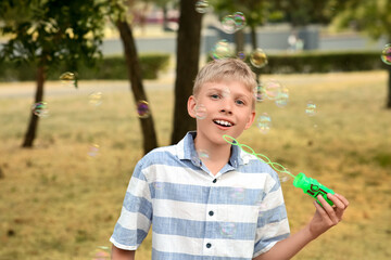 Sticker - Cute happy little boy blowing soap bubbles in park