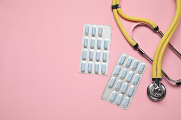 Wall Mural - Antibiotic pills in blisters and stethoscope on pink background, flat lay. Space for text