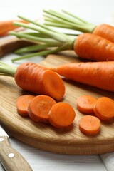 Wall Mural - Whole and cut fresh carrots on white wooden table, closeup