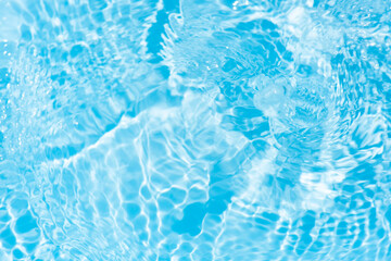 Bluewater waves on the surface ripples blurred. Defocus blurred transparent blue colored clear calm water surface texture with splash and bubbles. Water waves with shining pattern texture background.