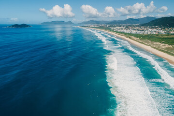 Poster - Beach coastline and ocean with waves on sunny day in Brazil. Aerial view of Morro das Pedras, Florianopolis