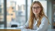 © nuengneng - A young female scientist with long blonde hair and glasses, arms crossed, standing confidently in a laboratory with a cityscape view.