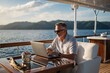© LIFE LINE - A mid-age male working on laptop computer on deck of a luxury yacht. Remote working concept
