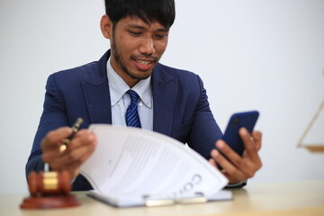 Asian male lawyer reading time limit law, giving advice, tax office, law firm, judge, legal advisor, lawyer working in office, judge knocking wood with lawyer for justice, contract