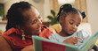 © AzeemudDeen/peopleimages.com - Smile, grandmother and child with book for education, learning literature and fantasy storytelling in lounge. Black family, woman and girl with creative reading, support and language growth at house