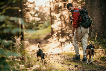 a middle-aged man with a small dogs hiking in the forest