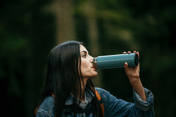 Wall Mural - Young woman enjoying hiking in nature and taking a break for drinking water 