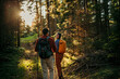 © La Famiglia - Couple with backpacks hiking together in forest during sunset
