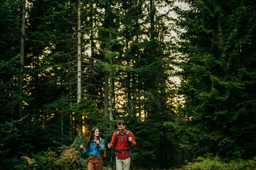 Wall Mural - Hiking couple follow the trail along forest ridge