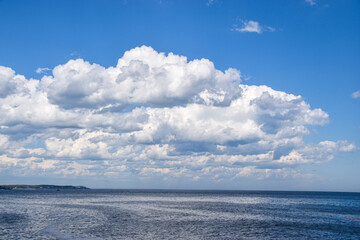 Expansive ocean view under a vast sky filled with fluffy white clouds.