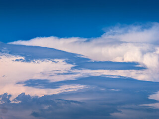 blue sky with white stormy cumulus clouds seen through low layer rain clouds.