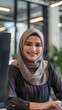 © Richafuji - Smiling Woman In A Hijab Working On A Computer suitable for business background, posters, wallpapers, banners, greeting cards, and advertising for business entities or brands.