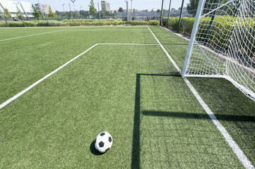 Wall Mural - Soccer ball on artificial bright and dark green grass at public outdoor football stadium