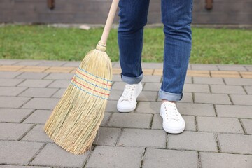 Wall Mural - Woman with corn straw broom sweeping pavement outdoors, closeup