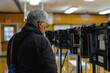 © Supranee - An elderly man thoughtfully examining voting machines in a community center, symbolizing civic engagement and participation.